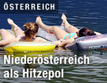 Zwei Frauen k&uuml;hlen sich auf ihren Luftmatratzen im Wasser ab