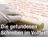 Schriftstück, gezeichnet von "Alfons Riedel, Bildhauer", wird ausgerollt