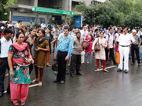 Menschen warten vor einer U-Bahnstation in Neu Delhi