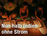 Jugendliche sitzen in Delhi am Boden und lesen bei Kerzenschein