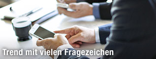 Hände mit Smartphones an einem Bürotisch
