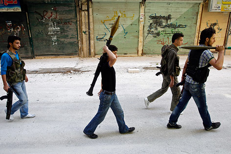 Mehrere Mitglieder der Freien Syrischen Armee patrollieren schwer bewaffnet durch eine Straße in Aleppo