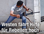 Mitglied der Freien Syrischen Armee mit Maschinengewehr an einer Hausecke