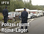 Polizei steht neben Karawane aus Wohnwagen