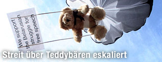 Teddyb&auml;r mit Fallschirm und Miniaturtransparent in der Luft