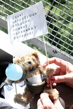 Teddybär mit Fallschirm und einem kleinen Transparent mit kyrillischer Schrift