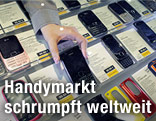 Eine Verkäuferin nimmt ein Smartphone aus dem Sortiment