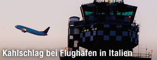 Silhouette eines startenden Flugzeugs neben einem Kontrollturm