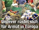 Hände legen in einem Supermarkt Produkte in einen Einkaufswagen