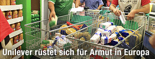 H&auml;nde legen in einem Supermarkt Produkte in einen Einkaufswagen