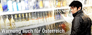 Ein Verkäufer verhüllt ein Regal mit hartem Alkohol mit durchsichtigem Plastik