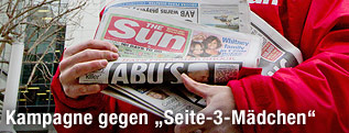 Kolporteur hält eine Ausgabe der englischen Boulevardzeitung The Sun in der Hand