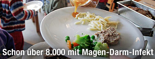 In einer Schule wird Soße auf einen Teller mit Essen gegossen