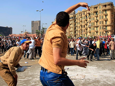 © AP/Khalil Hamra Ein Mann wirft auf dem Kairoer Tahrirplatz einen Stein auf Demonstranten
