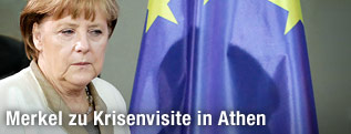 Die deutsche Bundeskanzlerin Angela Merkel steht neben einer EU-Fahne