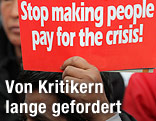 Schild "Stop making people pay for the crisis"