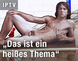 Mann geht an einer riesigen Skulptur eines nackten Manns vorbei
