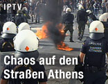 Polizisten stehen zwischen brennenden Gegenständen