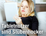 Frau liegt mit Tablet auf einer Couch