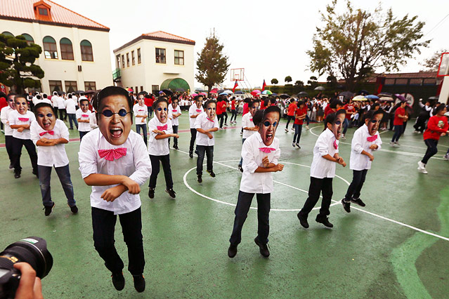 Personen mit Psy-Masken performen "Gangnam Style"