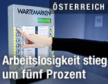 Frau drückt beim AMS eine Wartenummer