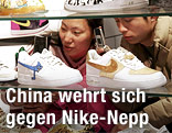 Chinesische Teenager sehen sich Nike-Sneaker in einem Glasregal an