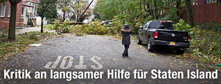 Frau steht auf einer Straße vor einem umgestürzten Baum