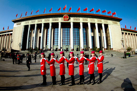 Frauen in roten Uniformen stehen vor der Große Halle des Volkes in Peking