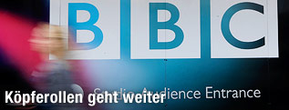 Frau geht an BBC-Schild vorbei