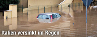 Fast vollständig versunkenes Auto vor einem Wohnhaus