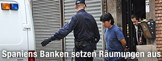 Ein Mann wird von spanischer Polizei nach einer Zwangsräumung aus dem Haus geführt