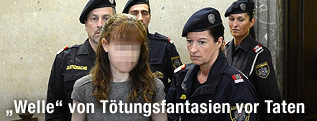 Angeklagte wird von Polizisten in den Gerichtssaal geführt