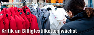 Eine Frau interessiert sich für Kleidungsstücke an einem Kleiderständer