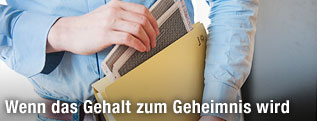 Mann gibt Gehaltsabrechnung in eine Mappe