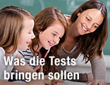 Eine Lehrerin erkl&auml;rt zwei Sch&uuml;lerinnen eine Aufgabe