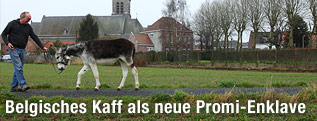 Ein Mann spaziert mit seinem Esel auf einem Feldweg nahe der Kirche in Nechin