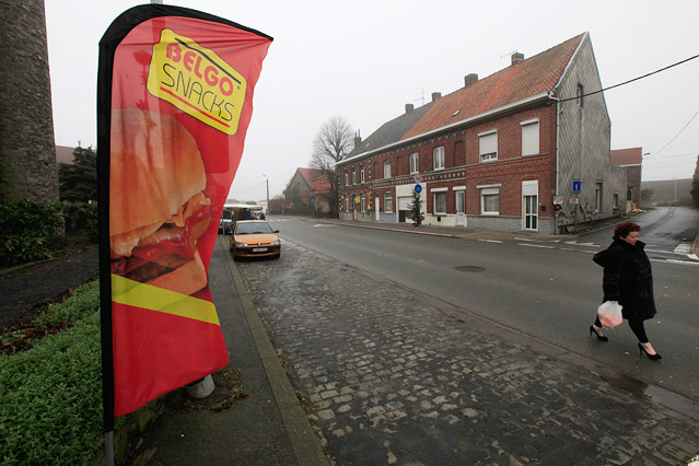© Reuters/Pascal Rossignol Eine Frau spaziert durch die Straßen von Nechin an einer Fast-Food-Kette-Werbung vorbei