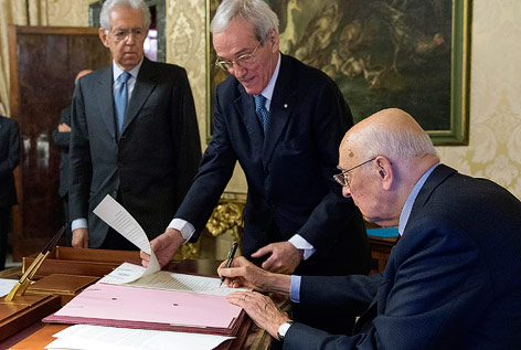 Der italienische Präsident Napolitano unterzeichnet Dokumente neben Premier Monti