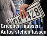 Person h&auml;lt eine alte Nummerntafel in der Hand