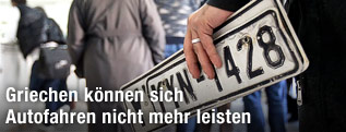 Person h&auml;lt eine alte Nummerntafel in der Hand