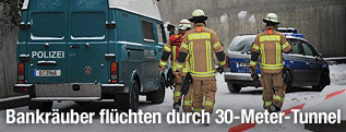 Polizeiautos und Feuerwehrmänner hinter einer Absperrung
