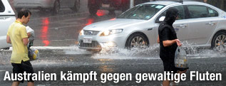 Menschen und Autos auf überfluteter Straße