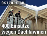 Feuerwehrleute in einem Krankorb neben einer Dachlawine