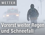 Ein Spazierg&auml;nger auf der schneeverwehten Stra&szlig;e