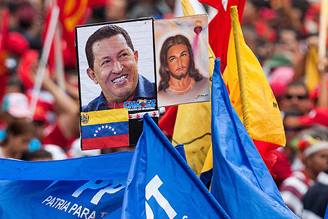 © APA/EPA/EFE/Miguel Gutierrez Anhänger halten ein Bild von Hugo Chavez neben einem Bild von Jesus Christus in die Höhe