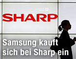 Frau steht vor Sharp-Logo