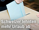 Kuvert wird in Wahlurne gesteckt