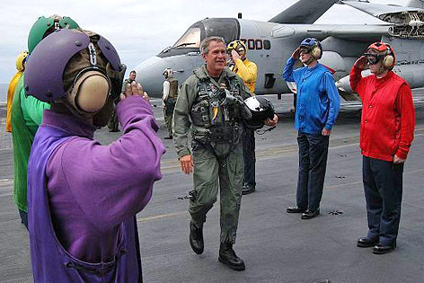 © APA/EPA/US Navy/Tyler J.Clements Ex-US-Präsident George W. Bush in Fliegermontur auf einem Flugzeugträger zwischen salutierendem Bordpersonal