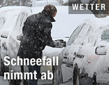 Mann bei eingeschneitem Auto