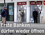 Passanten gehen an einer zypriotischen Bank vorbei